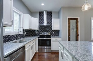 Enjoy cooking in this well-equipped kitchen with a stainless steel range hood, granite countertop, and ample cabinetry.