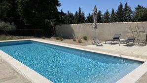 En rektangulär swimmingpool med klart blått vatten, omgiven av en terrass med kakelplattor.