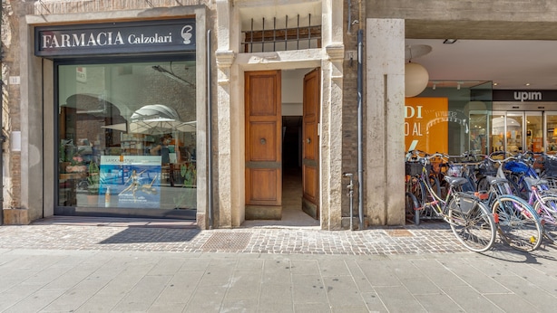 A storefront with a pharmacy named 'FARMACIA Calzolari' and a bike rental service 'upim' nearby.