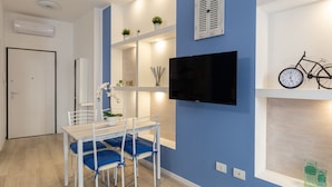 A modern living room with a dining area, a mounted TV, and a bicycle decoration on the wall.