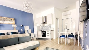 A modern living room with a sofa, a glass coffee table, and a dining area with chairs and a table.