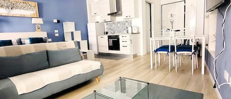 Una sala moderna con sofá, una mesa de centro de vidrio y un comedor con sillas y mesa.