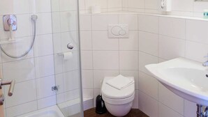 A bathroom with a glass shower enclosure, a toilet, and a sink.