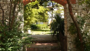 A stone archway leading to a courtyard with a stone wall, steps, and greenery. - Casa dos Arrábidos - Turismo em Espaço Rural (Torres Novas)