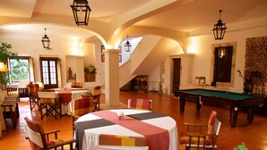 A dining area with tables and chairs, a pool table, and a staircase leading to an upper level. - Casa dos Arrábidos - Turismo em Espaço Rural (Torres Novas)