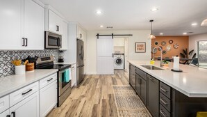 A modern kitchen with white cabinets, stainless steel appliances, and a central island. - *Heated Pool Available* | South Scottsdale Paradise (Scottsdale)