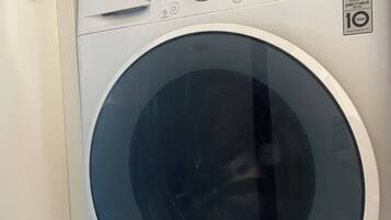 A front view of a white LG washing machine with a digital display, a control panel, and a 10-year warranty sticker.