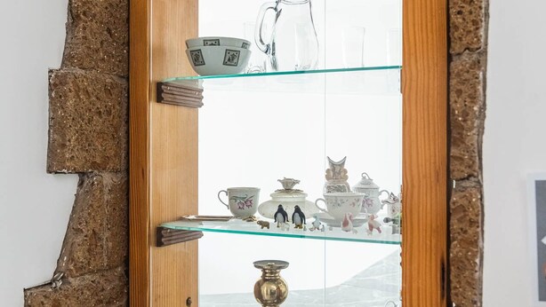 Ein Zimmer mit einer Holztür, die zu einer Vitrine mit verschiedenen Keramikgegenständen führt.