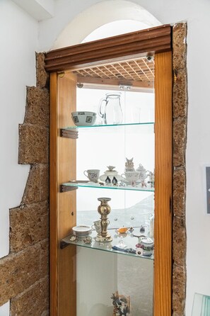 A room with a wooden door leading to a glass display case containing various ceramic items.
