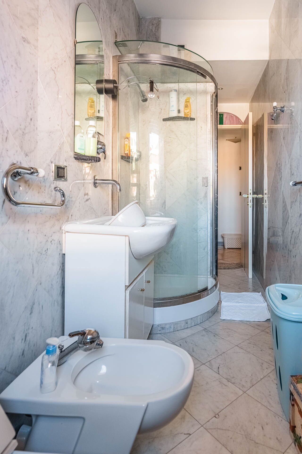 A modern bathroom with a glass-enclosed shower, a white sink, and a bidet.