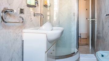 A modern bathroom with a glass-enclosed shower, a white sink, and a bidet.