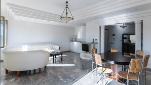 Ein modernes Wohnzimmer mit einem weißen Sofa, einem Esstisch mit Stühlen und einem durchgehenden Durchgang zur Küche.