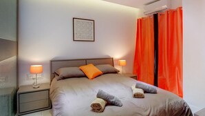 Un lit bien fait, avec deux oreillers, une lampe de chevet et des serviettes enroulées posées sur le lit.