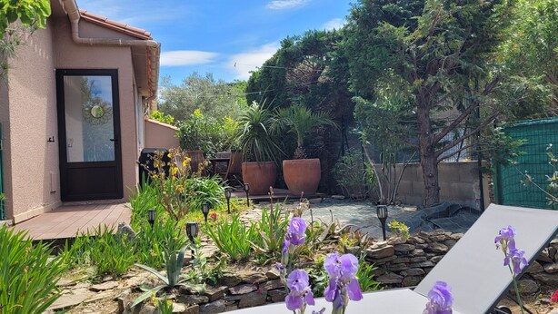 A patio with a stone pathway, potted plants, and outdoor furniture.