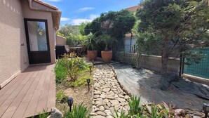 A patio area with a stone pathway, potted plants, outdoor furniture, and a swimming pool.