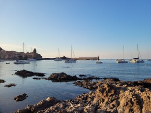A coastal marina with boats, rocky shore, and historic buildings in the background. - A magnificent three-bedroom apartment with panoramic ocean views. (Collioure)