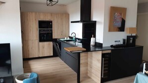 A modern kitchen with wooden cabinetry, a built-in oven, and a black countertop.