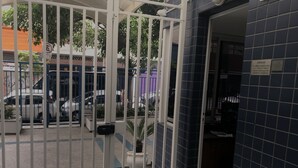 A gated entrance with a tiled wall and a signboard. - Apto Conforto C/ Netflix Amazon Prime Disponível (SP)
