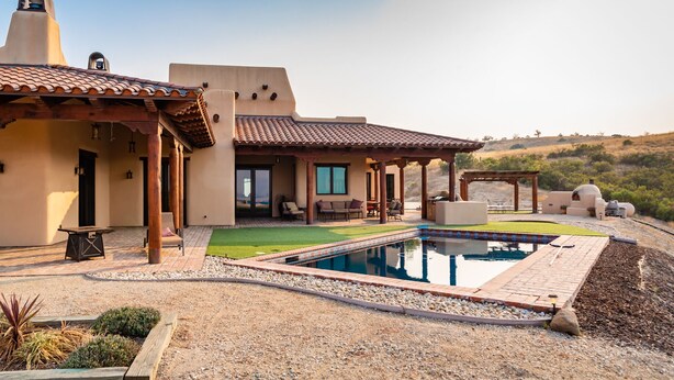 A house with a swimming pool, outdoor seating, and a view of the surrounding landscape.