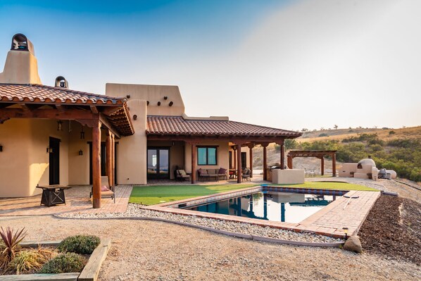 A house with a swimming pool, outdoor seating, and a view of the surrounding landscape.