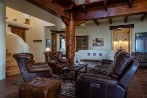 A spacious living area with leather furniture, a staircase, and a white sofa.