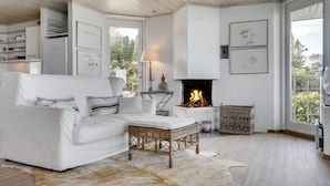 A white-themed living room with a sofa, a small table, a fireplace, and framed artwork on the walls. - 6 bedroom gorgeous home in Gilleleje (Gilleleje)