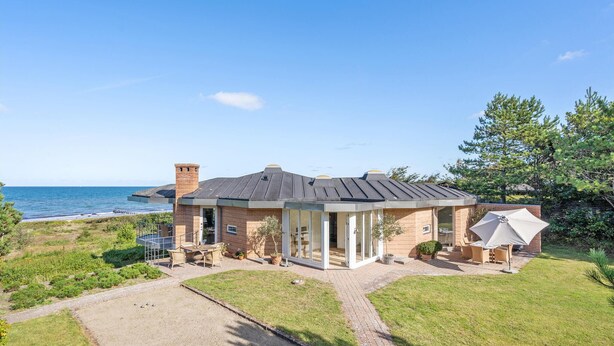 A two-story house with a brick exterior, a large glass door entrance, and a patio with outdoor furniture. - 6 bedroom gorgeous home in Gilleleje (Gilleleje)
