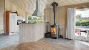 Et moderne køkken med trævægge, en central ø og en brændeovn.