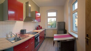 Eine moderne Küche mit roten Schränken, einer Edelstahl-Spüle und einem Fenster für natürliches Licht.