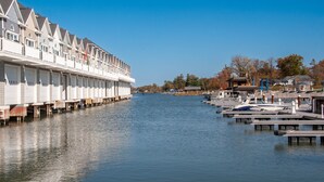 A waterfront hotel with multiple balconies, a dock with boats, and a clear blue sky.