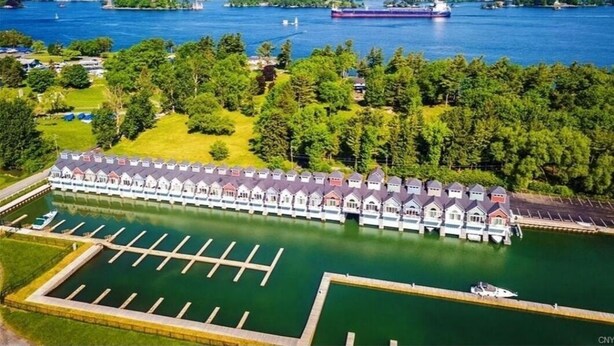 A waterfront hotel with a row of cabins, a marina, and a large ship in the background.