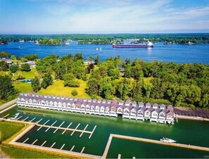 A waterfront hotel with a row of cabins, a marina, and a large ship in the background. - Townhouse on water with boathouse! (Alexandria Bay)