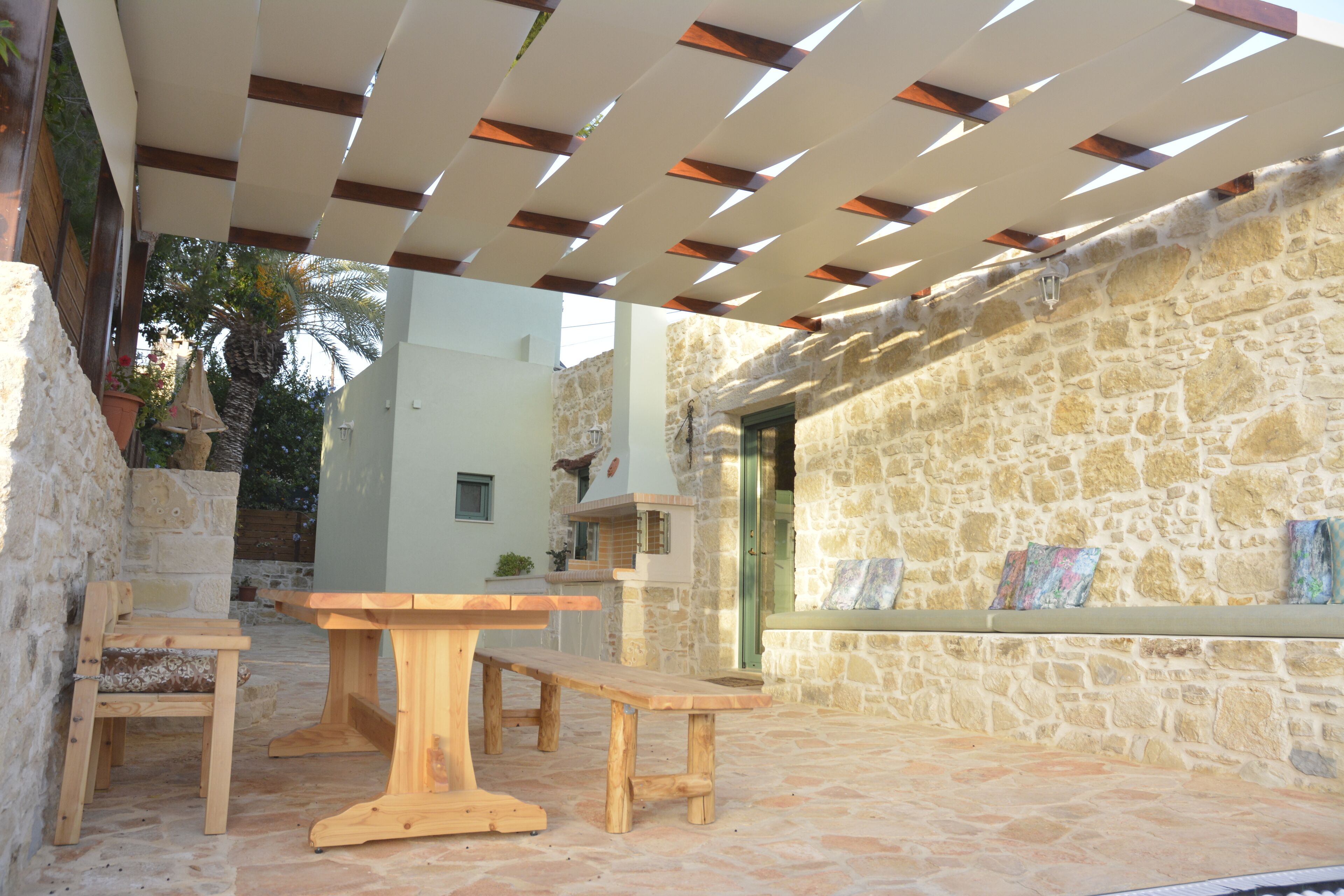 An outdoor patio area with stone walls, wooden benches, and a pergola.