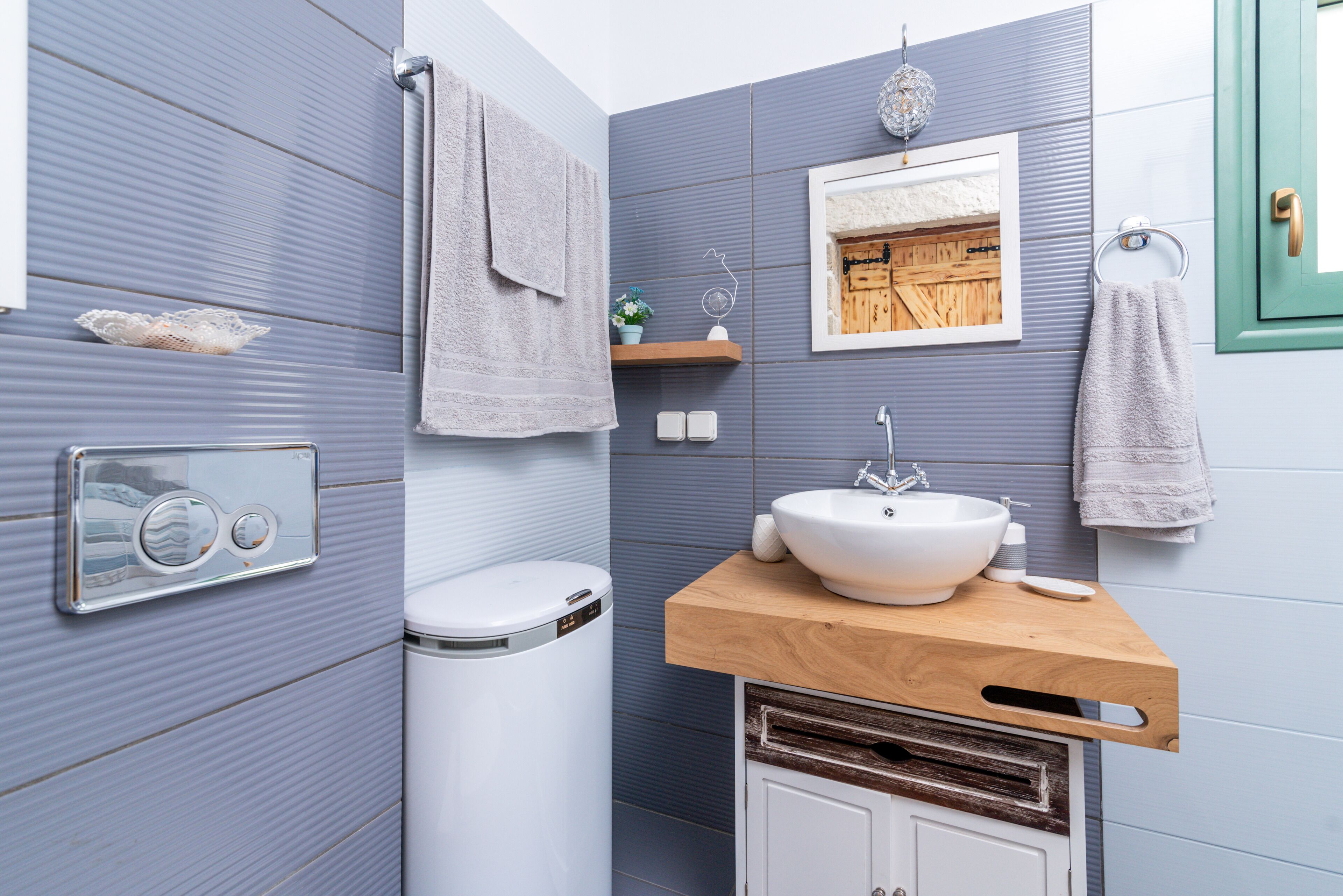 Une salle de bain au design moderne, comprenant des toilettes blanches, un meuble-lavabo en bois avec un évier et un porte-serviettes.