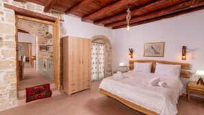 A bedroom with a wooden bed, stone walls, and a wooden ceiling. - Joakim's villa  (herakleion)