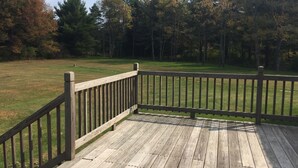A wooden deck with a railing overlooking a grassy area with trees. - Welcome to the Adirondacks (Boonville)