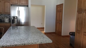 A kitchen with granite countertops, wooden cabinets, a stainless steel refrigerator, and a coffee maker. - Welcome to the Adirondacks (Boonville)