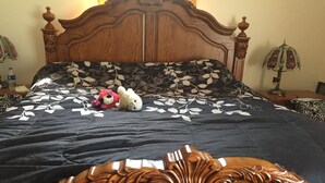A wooden bed with a floral bedspread, two stuffed animals, and a nightstand with a lamp. - Welcome to the Adirondacks (Boonville)