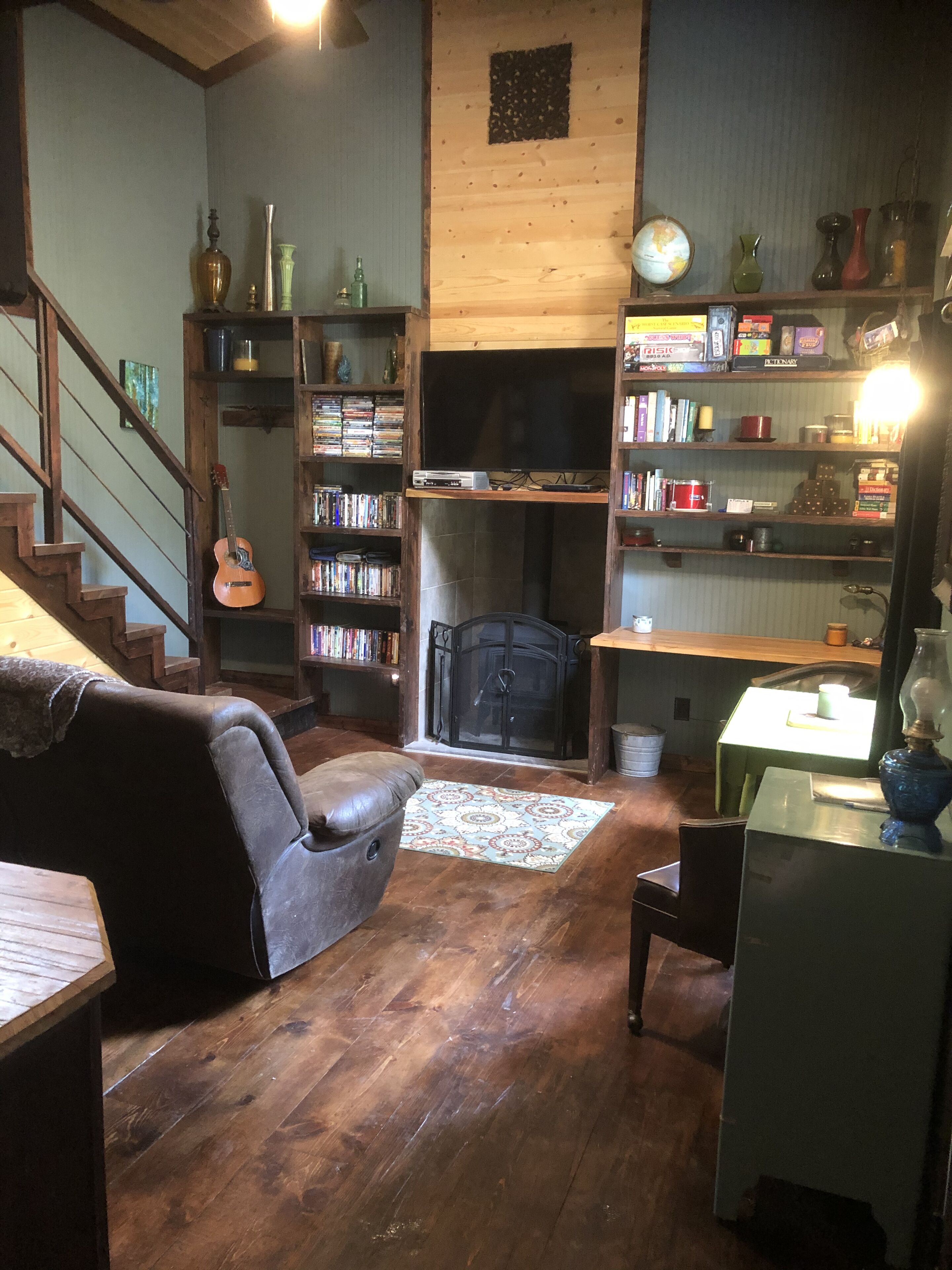 Una sala de estar acogedora con chimenea, estanterías, una guitarra y un televisor.