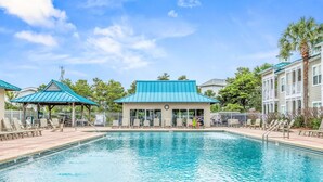 Una piscina con sillones de descanso y un pabellón cubierto.