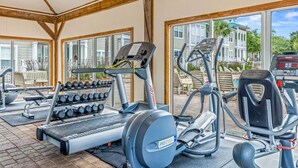 Un espacio exterior cubierto para gimnasio con equipo de ejercicio, incluyendo cintas de correr, elípticas y mancuernas.