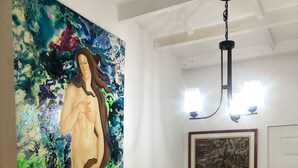 A staircase with a wooden handrail, a large abstract painting, a framed artwork, and a chandelier. - Hermoso Duplex Bovedas (Cartagena)