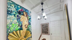 A staircase with a large abstract painting, a framed artwork, and a chandelier. - Hermoso Duplex Bovedas (Cartagena)