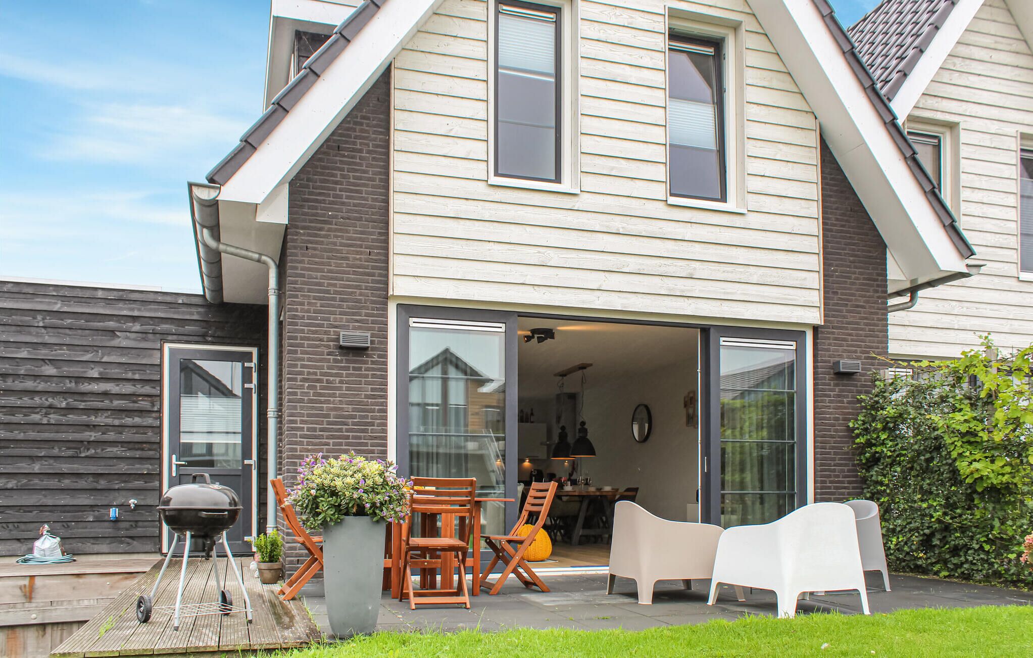 Een huis met een patio, compleet met buitenmeubilair, een barbecue en een grote bloemenplanter.