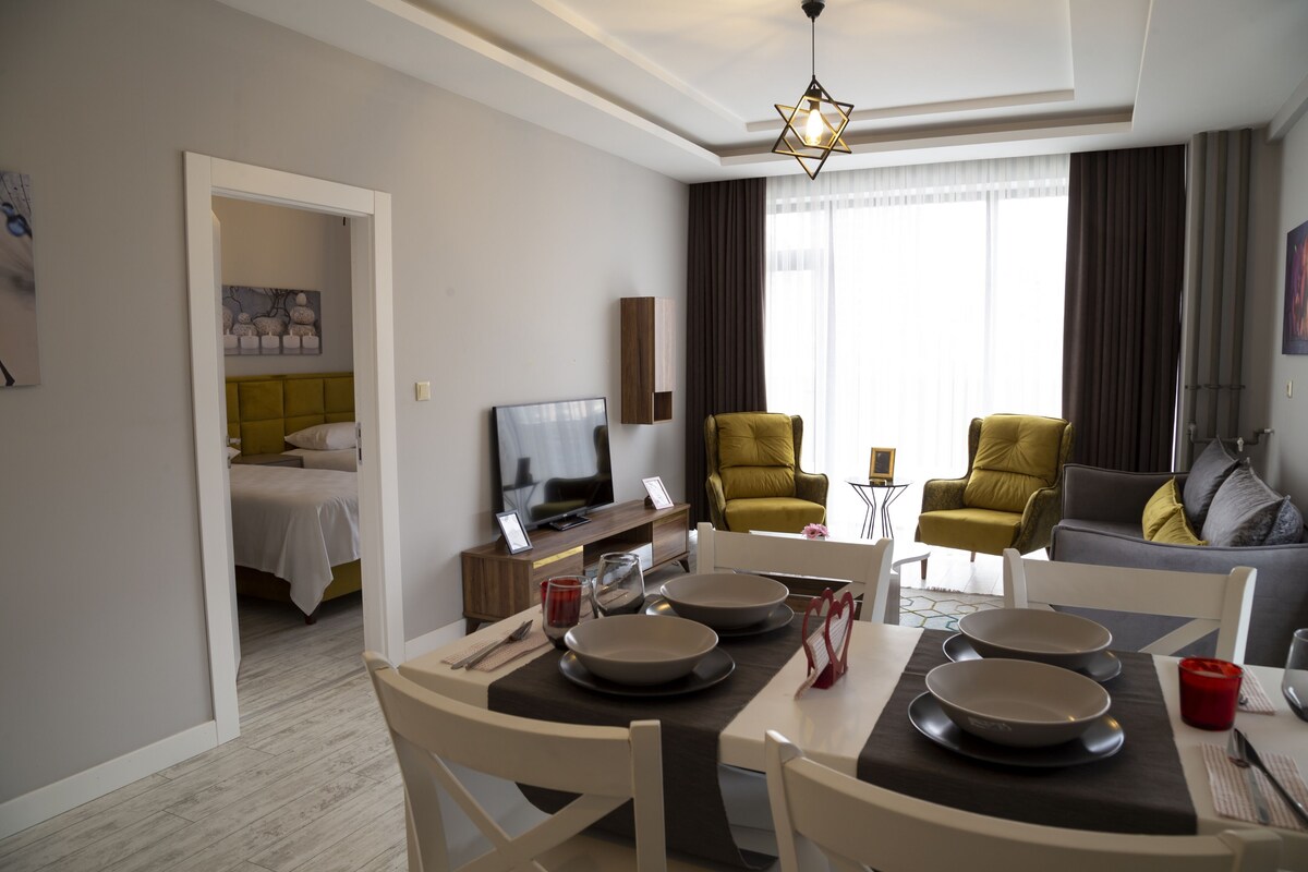 A modern hotel room with a dining area, a sofa, and a television.