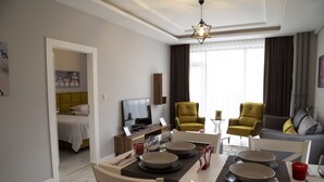 A modern hotel room with a dining area, a sofa, and a television. - Hatton Suites Esenboga (Ankara)