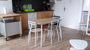 Une cuisine compacte équipée d’un four à micro-ondes, d’un évier et de placards. Un coin repas avec une table et des chaises est également disponible.