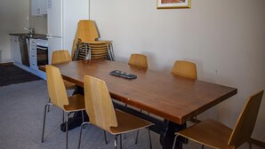 Ein Essbereich mit Holztisch und sechs Stühlen, im Hintergrund eine Küche und ein gerahmtes Bild an der Wand.