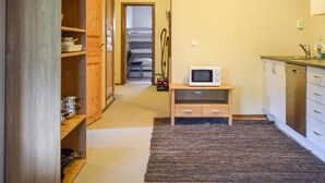 Eine kleine Küche mit Mikrowelle, Holzschränken und einem Teppich.