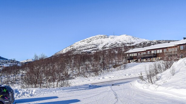 Ein schneebedeckter Berg mit einem Gebäude im Vordergrund.